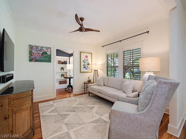 living room with ornamental molding, ceiling fan, and light wood-type flooring