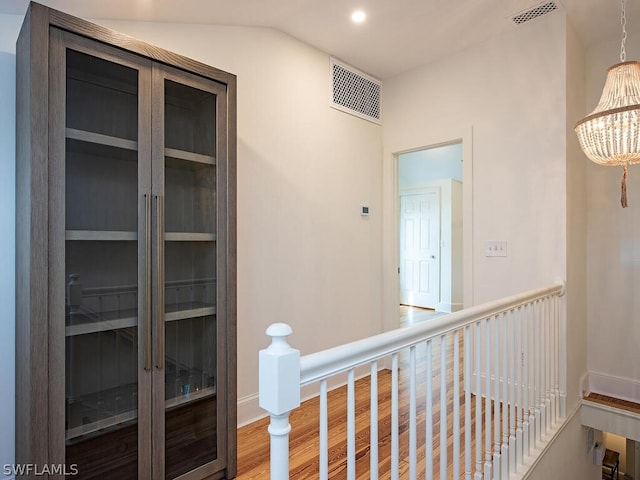 hallway with lofted ceiling, a chandelier, and light hardwood / wood-style floors