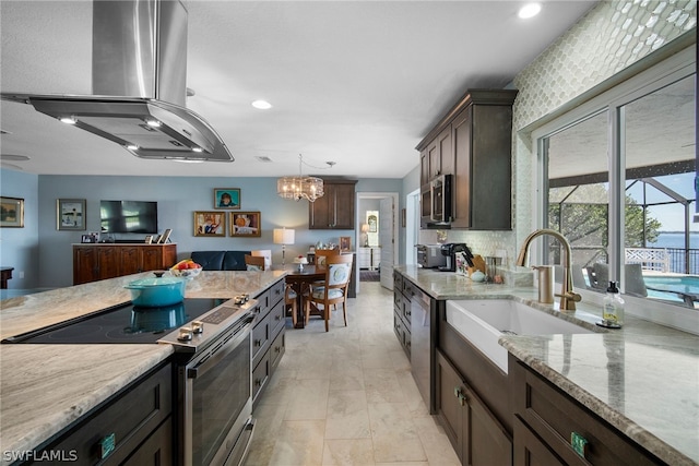 kitchen with hanging light fixtures, backsplash, a notable chandelier, appliances with stainless steel finishes, and island range hood