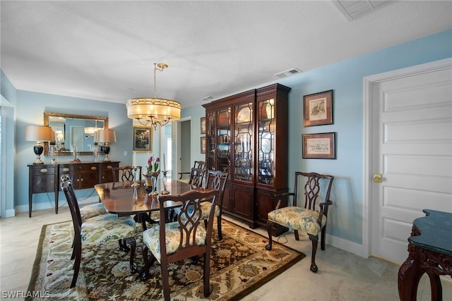 dining room with an inviting chandelier and a textured ceiling