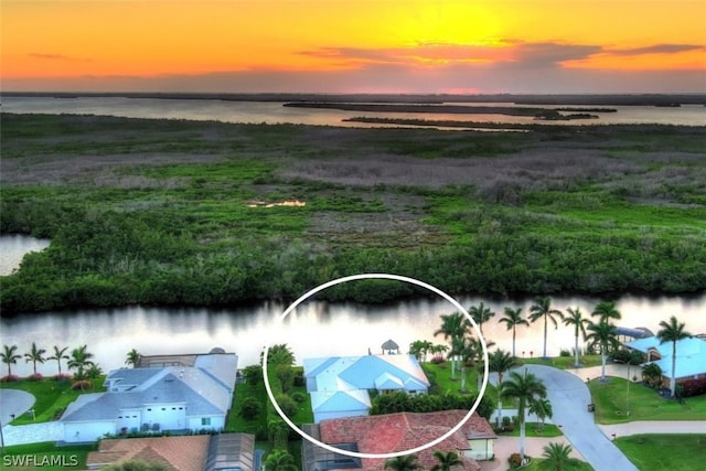 aerial view at dusk featuring a water view