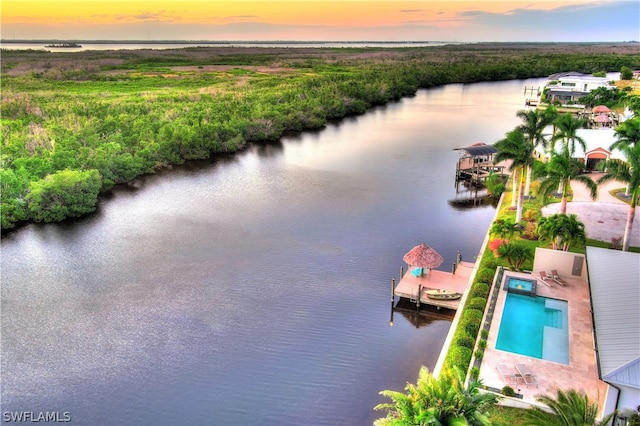 aerial view at dusk featuring a water view