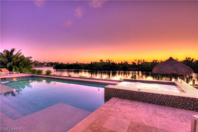 pool at dusk with a patio, a water view, an in ground hot tub, and a gazebo