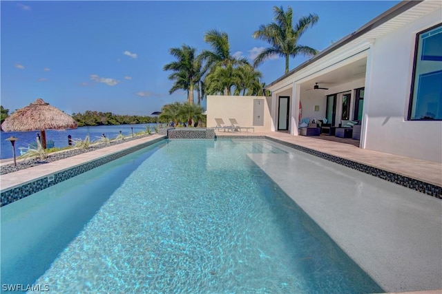 view of swimming pool with ceiling fan, a patio, and a water view