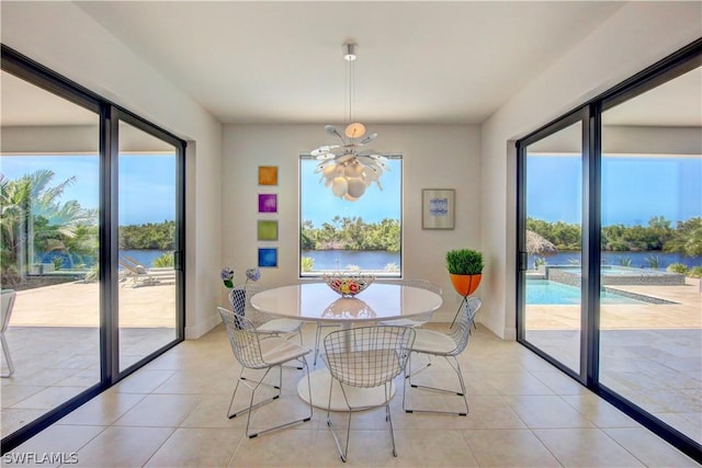 tiled dining area featuring a notable chandelier and a water view