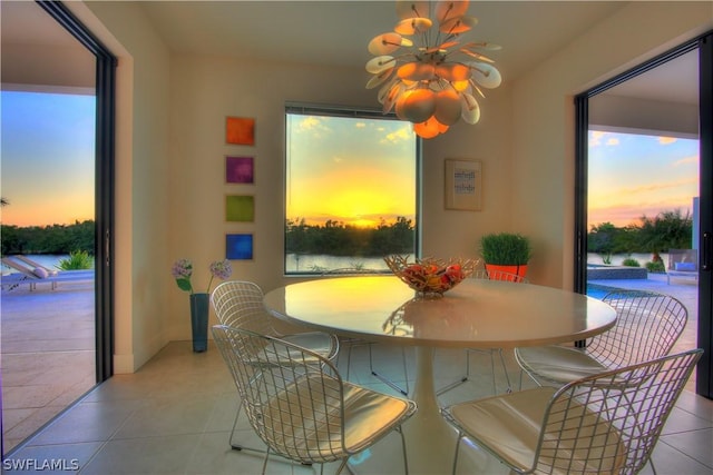 dining space with light tile patterned flooring and a water view