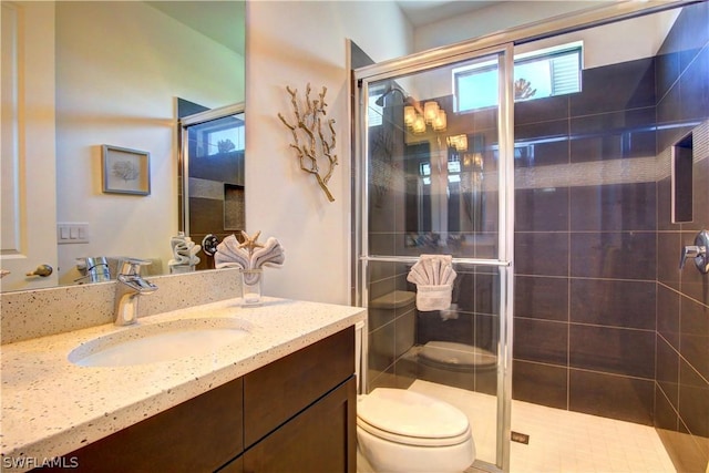 bathroom featuring a shower with door, vanity, and toilet