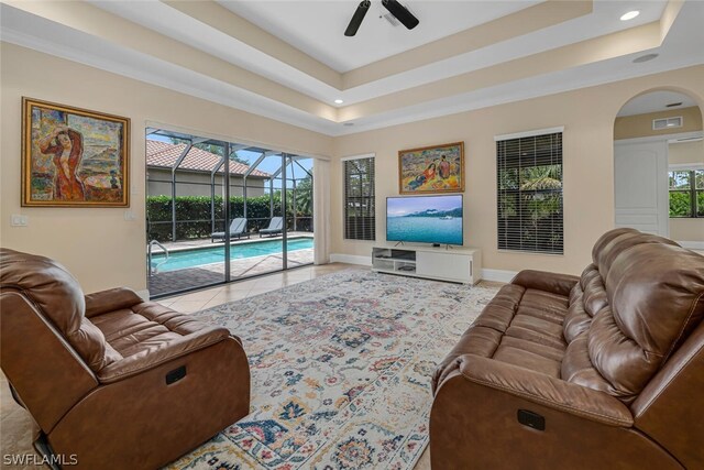 living room with ceiling fan, light tile flooring, and a raised ceiling