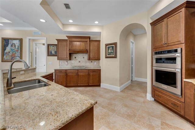 kitchen featuring tasteful backsplash, stainless steel double oven, light stone countertops, sink, and light tile flooring