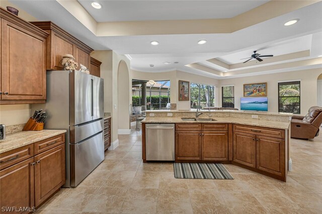 kitchen with ceiling fan, plenty of natural light, a raised ceiling, and stainless steel appliances