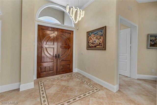 tiled foyer entrance with an inviting chandelier and crown molding