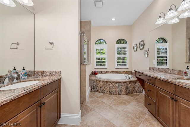 bathroom featuring a relaxing tiled bath, vanity, and tile floors