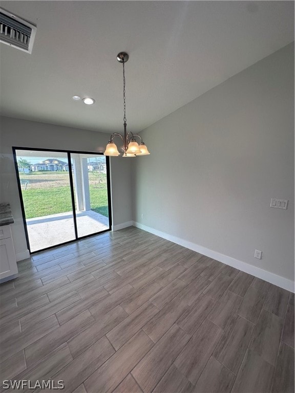 empty room with light hardwood / wood-style floors and an inviting chandelier