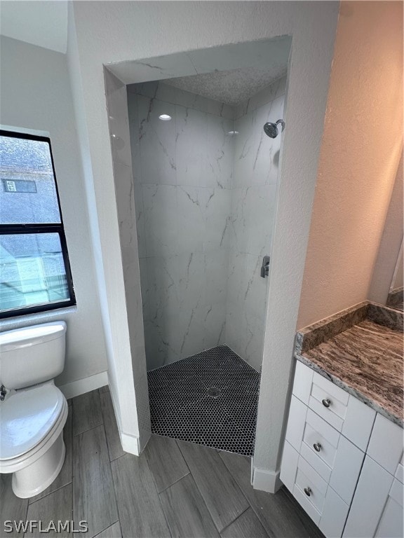 bathroom featuring toilet, a tile shower, and a wealth of natural light