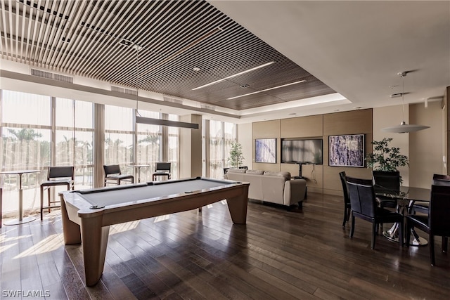 game room with a tray ceiling, pool table, and dark hardwood / wood-style flooring