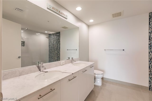 bathroom featuring tile flooring, double sink, toilet, and vanity with extensive cabinet space