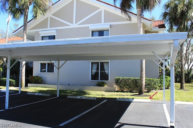 view of parking / parking lot with a carport and a yard