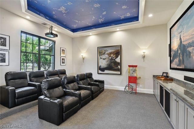 home theater featuring a raised ceiling and light carpet