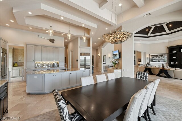 dining space featuring coffered ceiling, light tile flooring, a tray ceiling, and a towering ceiling