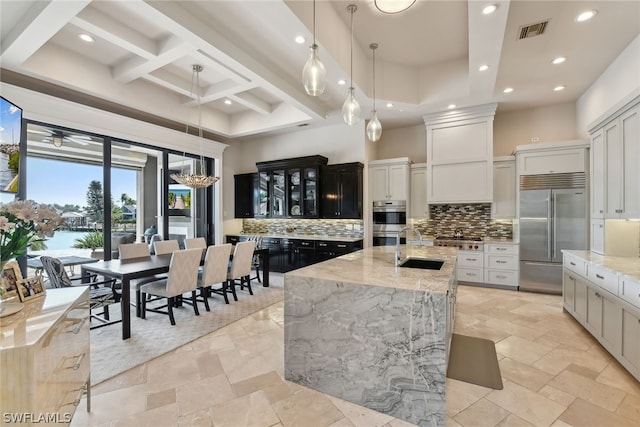 kitchen with backsplash, an island with sink, appliances with stainless steel finishes, and light tile floors