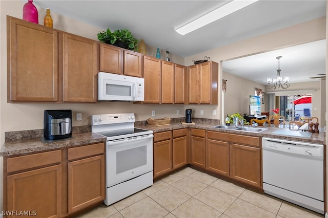 kitchen with hanging light fixtures, white appliances, light tile flooring, sink, and an inviting chandelier