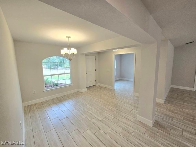 empty room with light wood finished floors, a notable chandelier, and baseboards