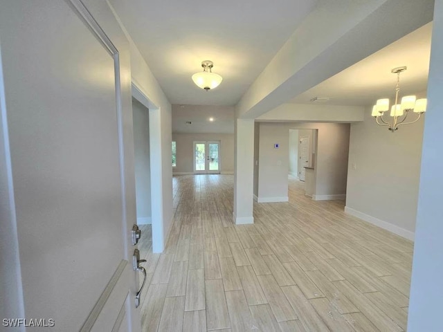 unfurnished room with wood finish floors, baseboards, and a notable chandelier