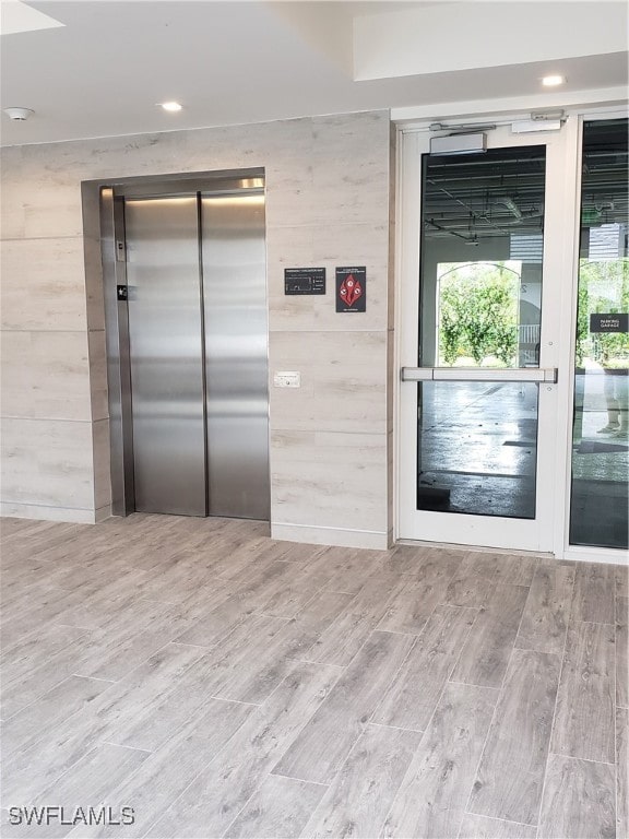 unfurnished room with light wood-type flooring and elevator