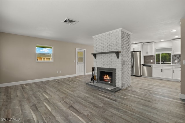 unfurnished living room featuring hardwood / wood-style floors and a brick fireplace