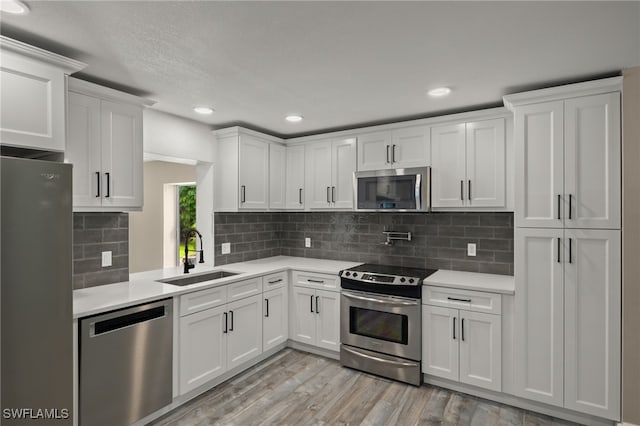 kitchen featuring appliances with stainless steel finishes, light hardwood / wood-style flooring, sink, and white cabinets