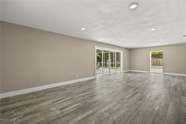 unfurnished room with a textured ceiling and dark hardwood / wood-style floors