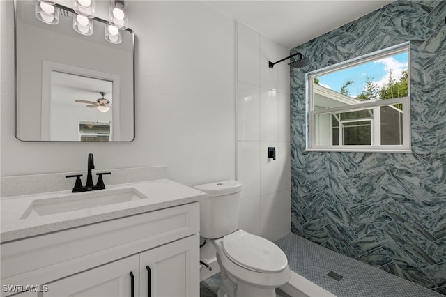 bathroom with vanity, toilet, a tile shower, and ceiling fan