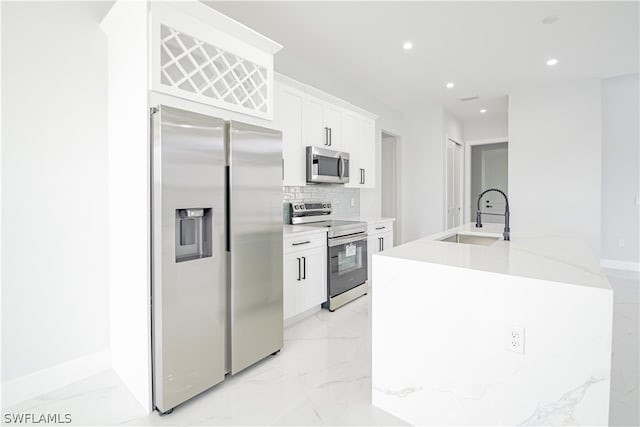 kitchen featuring white cabinets, backsplash, appliances with stainless steel finishes, light tile floors, and sink