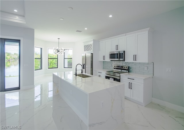 kitchen featuring light tile floors, white cabinets, sink, stainless steel appliances, and a kitchen island with sink