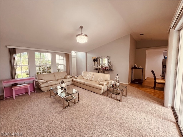 living room featuring a chandelier, light colored carpet, and vaulted ceiling