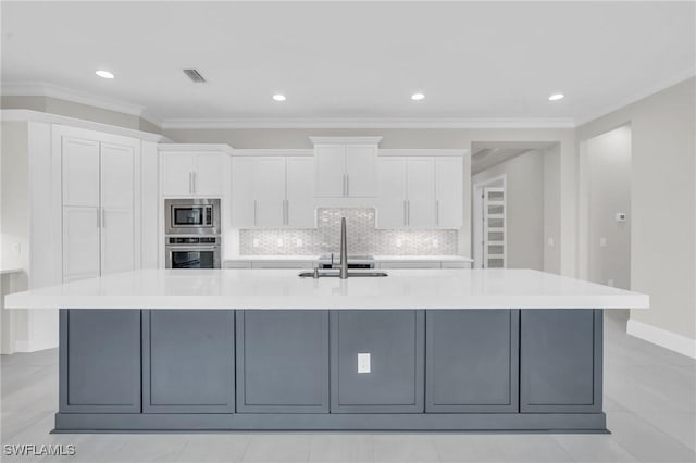 kitchen featuring appliances with stainless steel finishes, a spacious island, a sink, and white cabinets