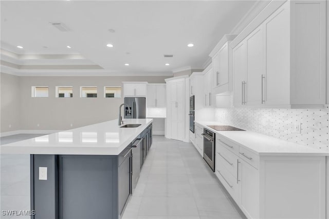 kitchen with appliances with stainless steel finishes, backsplash, a large island with sink, and white cabinets