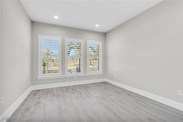 empty room featuring recessed lighting, wood finished floors, and baseboards