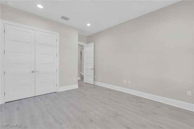 unfurnished bedroom with recessed lighting, a closet, visible vents, wood finished floors, and baseboards