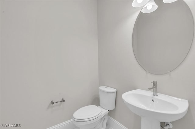 half bath featuring baseboards, a sink, and toilet