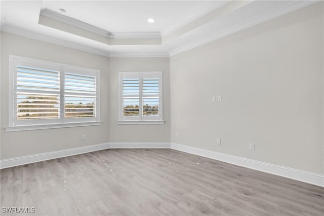 unfurnished room featuring baseboards, a raised ceiling, and crown molding