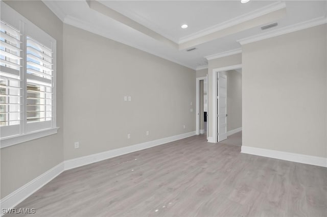 unfurnished room featuring baseboards, visible vents, a raised ceiling, and ornamental molding