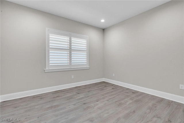 spare room with baseboards, wood finished floors, and recessed lighting