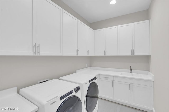 laundry room featuring separate washer and dryer, a sink, and cabinet space