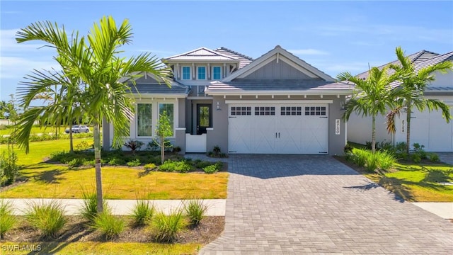 view of front of house featuring a garage, decorative driveway, a front yard, and stucco siding