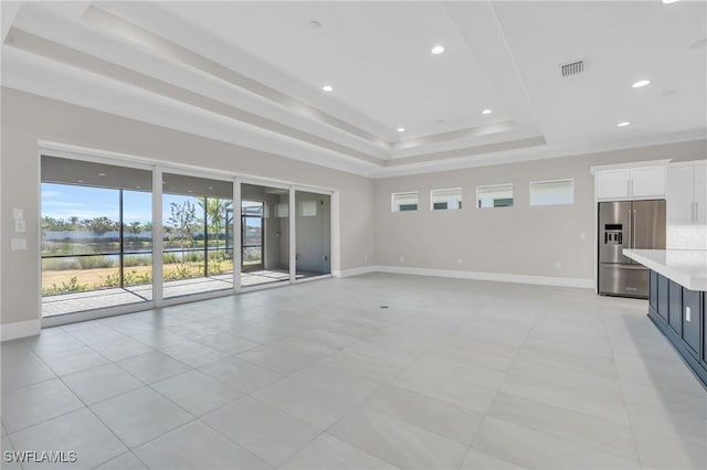 unfurnished living room with recessed lighting, a raised ceiling, visible vents, and baseboards