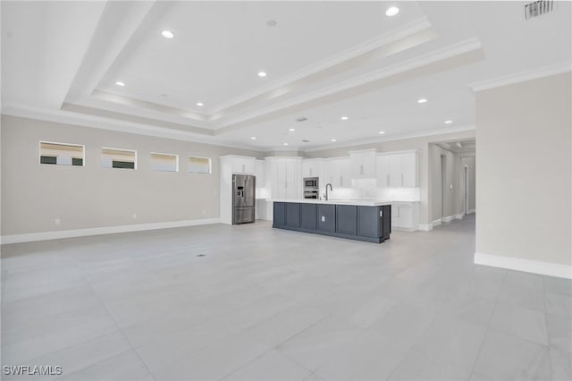 unfurnished living room featuring a raised ceiling, visible vents, a sink, and baseboards