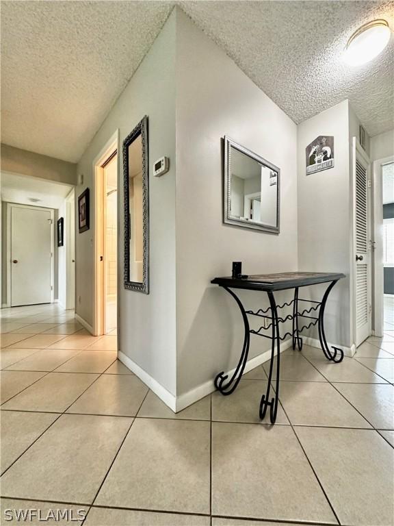 corridor featuring light tile patterned flooring and a textured ceiling