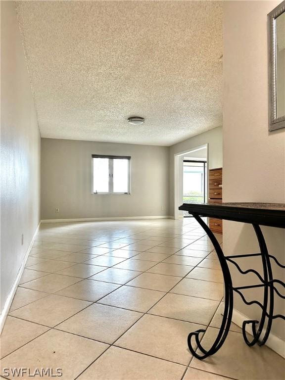 unfurnished room featuring a wealth of natural light, light tile patterned floors, and a textured ceiling