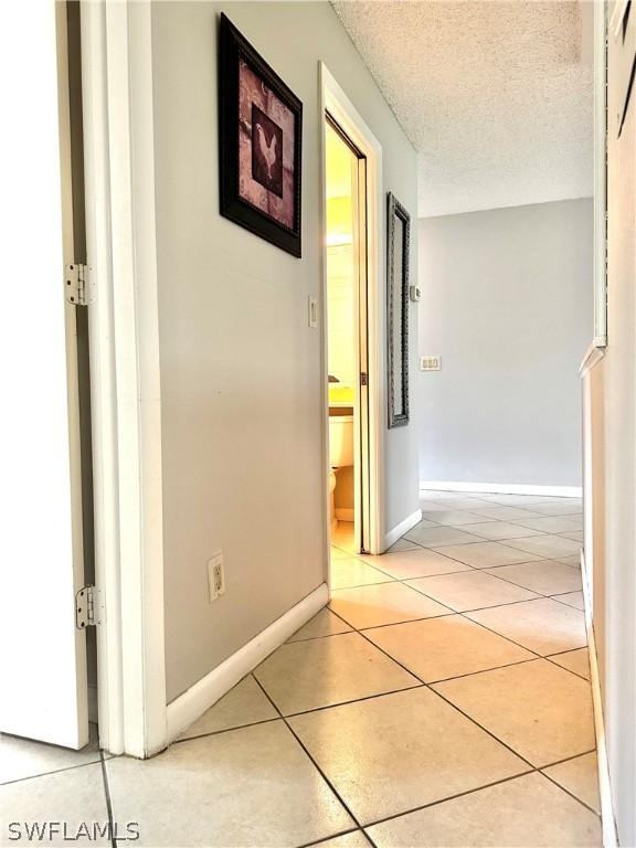 hallway with light tile patterned floors and a textured ceiling